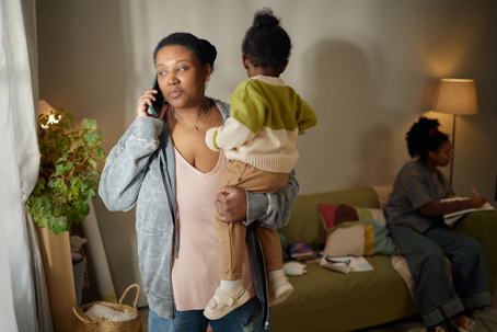 stressed mother on the phone while taking care of her kids