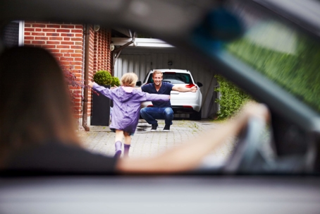 Daughter running to father while mom watches in car
