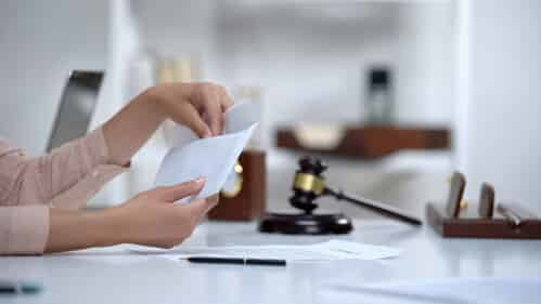 person putting money in an envelope next to a gavel
